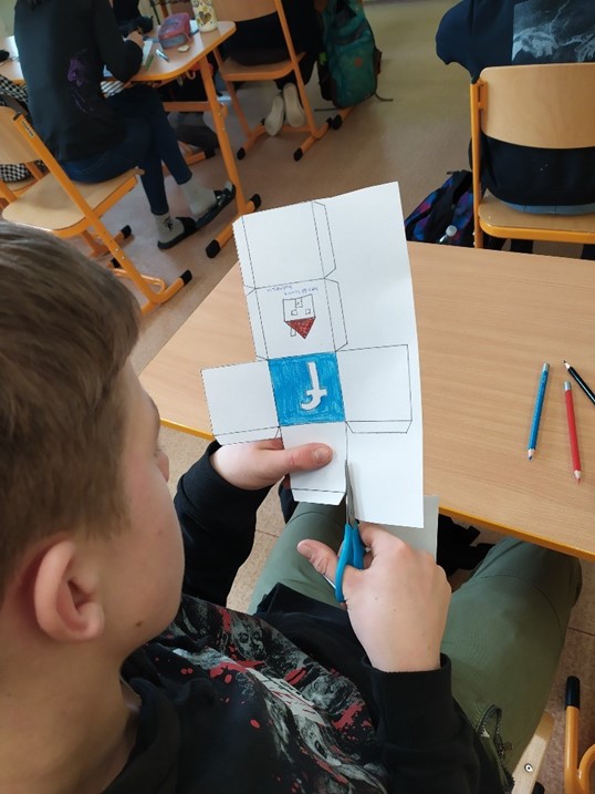 A young person cutting a paper game with the Facebook logo.