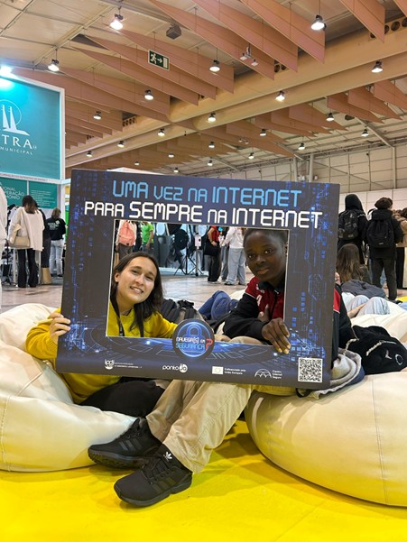 Group picture with two young people and a promotional frame of SIC Portugal at the fair