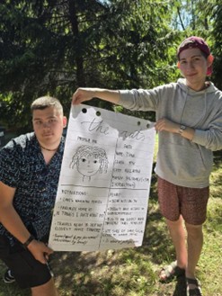 Two teenagers holding a piece of paper with words and drawings
