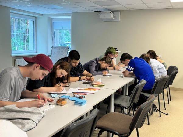 A group of nine teenagers working on crafts on a shared table