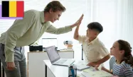 A teacher high-fiving a student in a classroom with a laptop