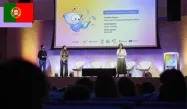 Three speakers on stage in front of a screen presenting the creation of Portugal’s Linha Internet Segura (LIS) chatbot.