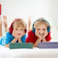 Two young boys with headphones on and tablets in front of them