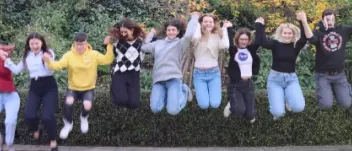 A group of BIK youth participants all holding hands and jumping