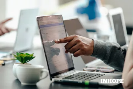 Hand pointing at a laptop screen with INHOPE logo superimposed
