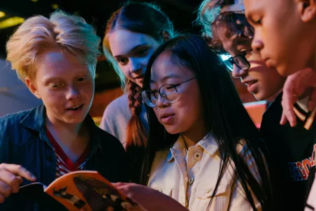 Group of adolescents discussing around a magazine