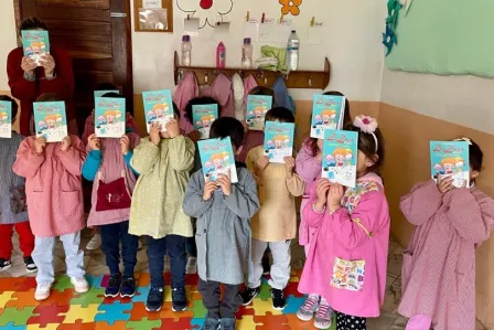 Group picture of young children participating in the activities, holding a book to cover their faces given the young age