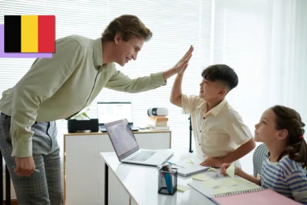 A teacher high-fiving a student in a classroom with a laptop