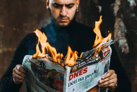 Man reading a newspaper with flames coming from the top of it