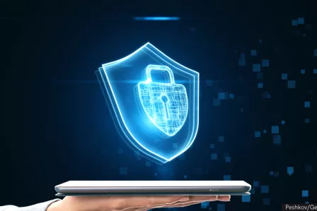 Hands holding a laptop with a virtual shield on top