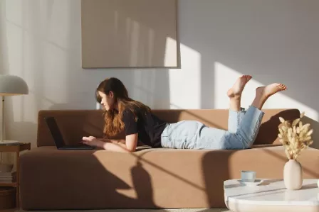 Girl lying on a sofa using a laptop