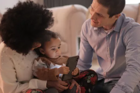 Two parents with a young baby, holding a mobile phone
