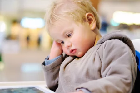 Toddler in a high chair, watching a tablet device