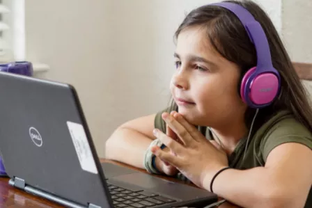 Young girl with headphones looking at a laptop