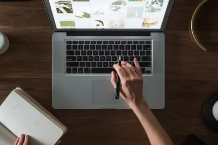 Birds eye view of a laptop on a desk, with a hand typing