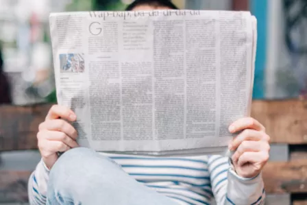 Person sitting on a bench while reading the newspaper