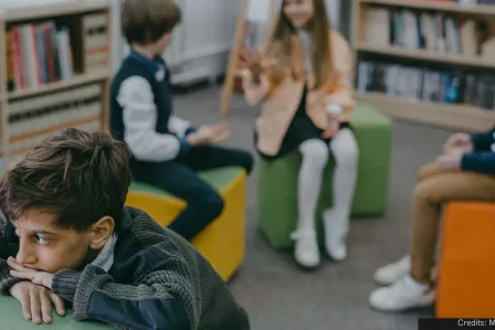 Child looking worried and isolated from the group of children behind him