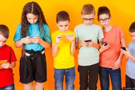 A group of six children of various ages, all looking at their own smartphones