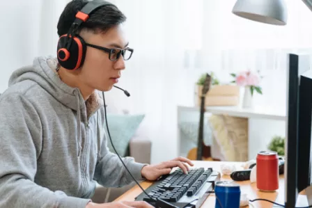 Teenage boy using a desktop computer wearing headphones and a mic