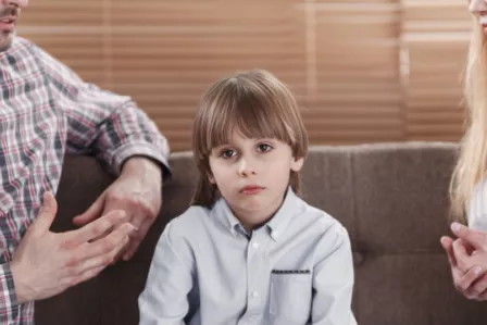 Young child sat between two adults having a conversation