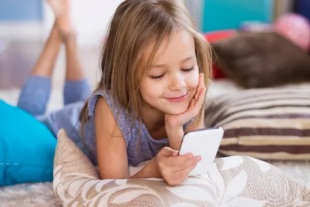 Young girl laying on the floor using a mobile phone