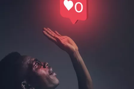 A young man trying to reach for a "likes" icon