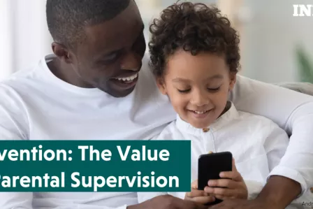 A parent and a child looking at a smartphone and smiling.