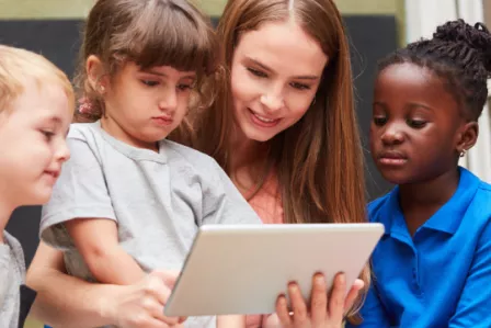 Three children and an adult looking at a tablet screen