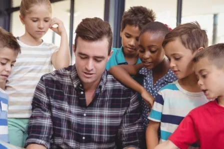 Children gathered around a teacher figure, taking instruction