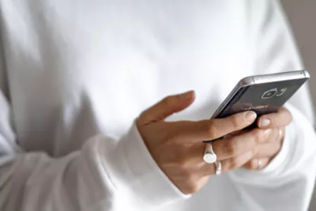 Girl holding Phone wearing white jumper