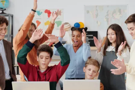 Group of cheerful young students and a teacher in front of two laptops