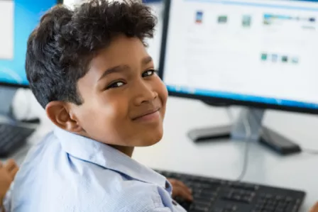Smiling child using a desktop computer in an educational setting