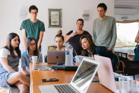 Group of young people gathered around a laptop screen