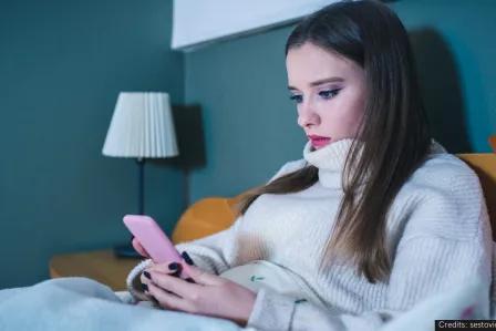 A teenager girl in bed looking at her phone