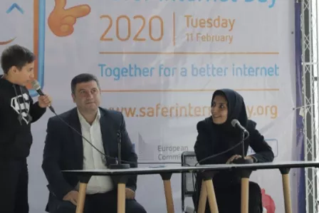 A young person, on stage, interviewing two speakers at the Safer Internet Day event in Iran
