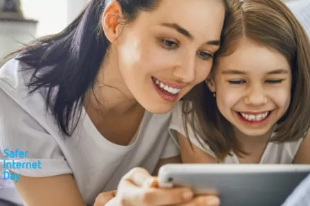Smiling parent and child, using a tablet together