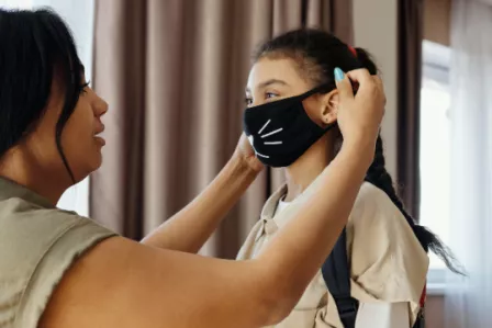 Mother putting a mask on her daughter's face