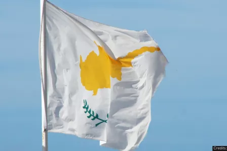 The writing "#SID2023" in the foreground of a waving Cypriot flag  