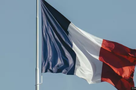 The writing "#SID2023" in the foreground of a waving French flag