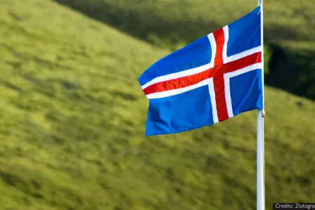 Icelandic flag waving on top of a pole, in front of a green background