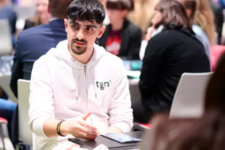 Young man sitting at a roundtable, many people sitting in the background