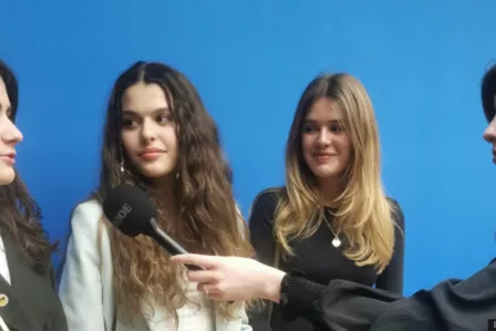 Teenage girls gathered around a microphone