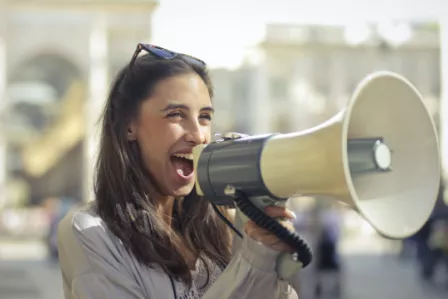 Young woman speaking through a loudspeaker