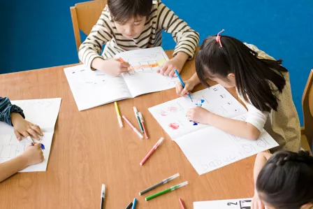 Children colouring a book on a table