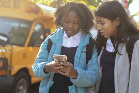 Two school girls checking something on a smartphone