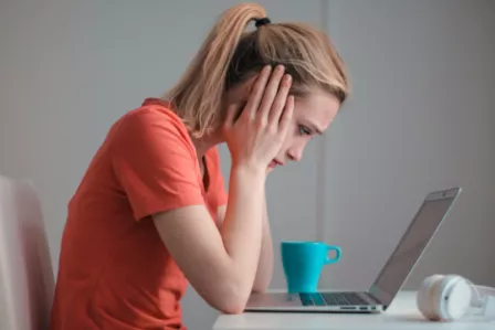 Girl with her head in her hands looking at a laptop screen