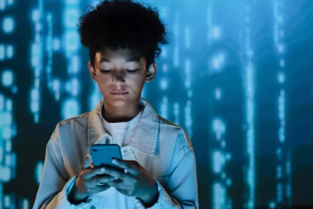 Young boy checking his mobile phone on a blue lights background