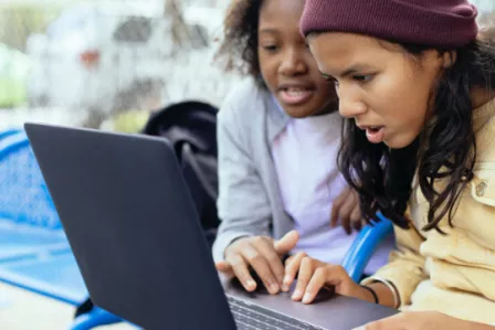 Teenagers using a laptop in a park setting
