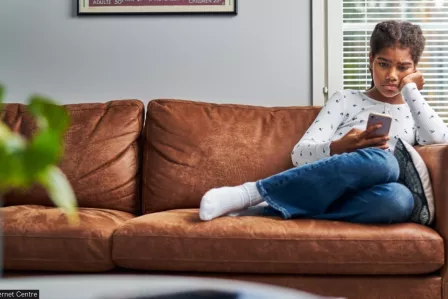 A girl sitting on a sofa and scrolling through her mobile