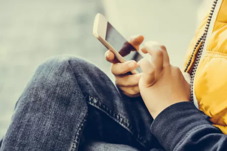 Hands of a young child tapping on a smartphone